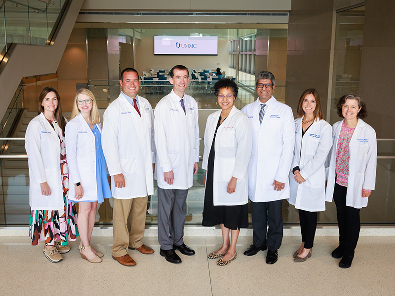 Eight program leaders standing inside the School of Medicine.